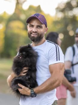 L'éducateur canin Tony Silvestre prenant une photo avec un chien Spitz noir