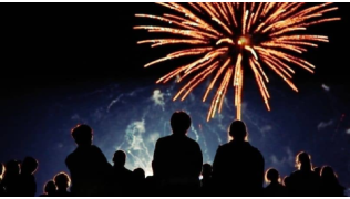 Une foule regarde un spectacle de feux d'artifices et pétards en pleine nuit