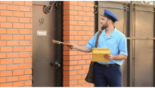 Un facteur dépose le courrier dans la boîte aux lettres d'une maison où il y a un chien
